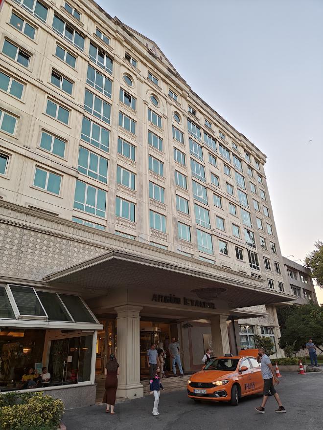The Akgün Hotel in Istanbul at dusk, where I stayed for the conference, with an orange taxi waiting under the canopy.