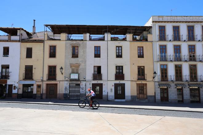 A cyclist crossing a stone square in Granada's old town.