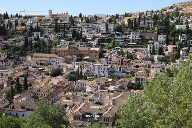View across the Darro valley to the Albaicín, with white houses descending the hillside.