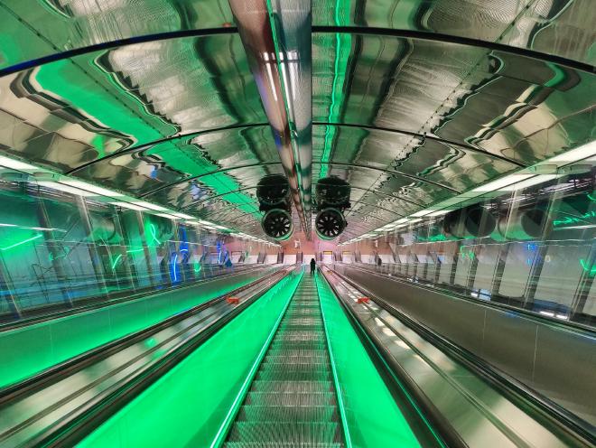 Futuristic green-lit escalator tunnel in Helsinki, on the way to a corporate workshop