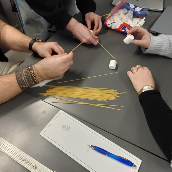 Spaghetti, marshmallows, and string laid out on a desk to start the marshmallow tower challenge